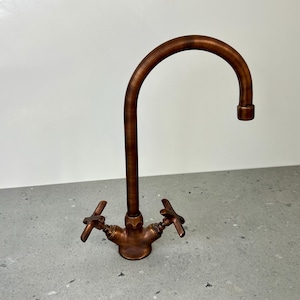 May include: A copper kitchen faucet with a high arc spout and two handles. The faucet has a brushed finish.