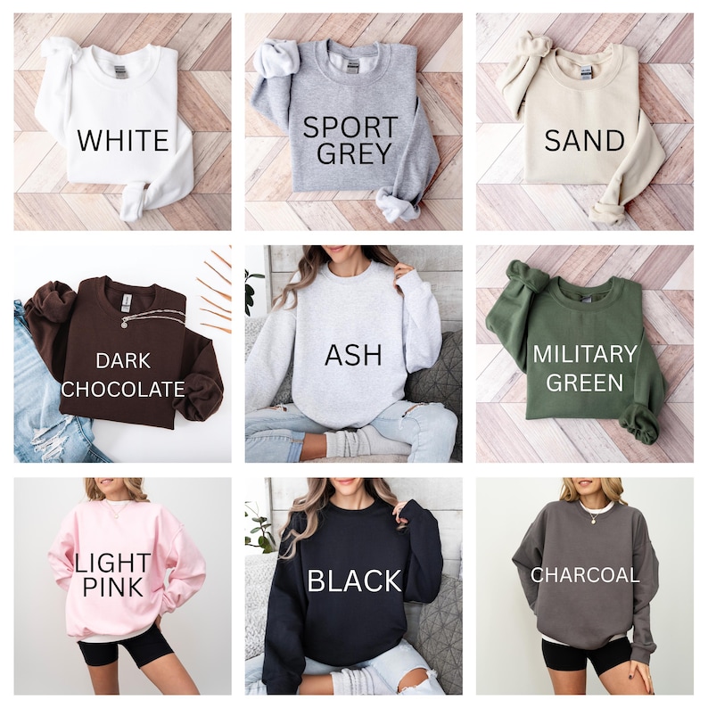 May include: A collection of nine crewneck sweatshirts in various colors. Colors include white, sport grey, sand, dark chocolate, ash, military green, light pink, black, and charcoal. Each sweatshirt has the color name printed on it.