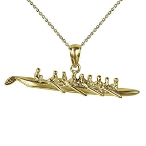 May include: A gold-tone necklace with a pendant shaped like a rowing crew boat with eight rowers. The pendant is detailed and realistic.