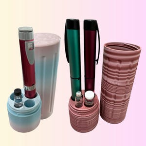 May include: An assortment of medical devices and accessories. The image features two pens, two cylindrical containers, and small vials. The pens are in shades of red and green. The containers are pink and blue. The vials are clear with white caps.