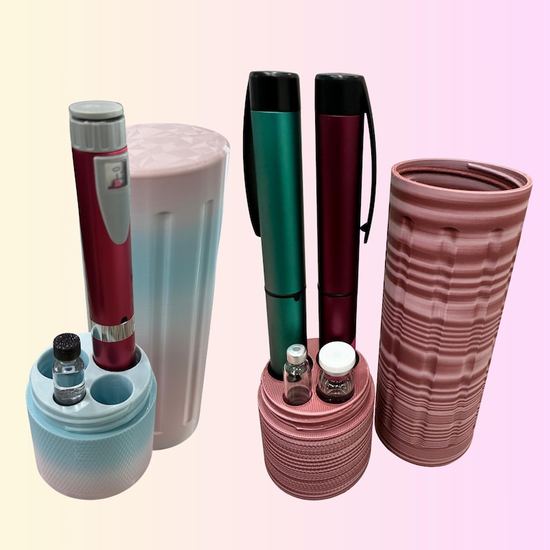 May include: An assortment of medical devices and accessories. The image features two pens, two cylindrical containers, and small vials. The pens are in shades of red and green. The containers are pink and blue. The vials are clear with white caps.
