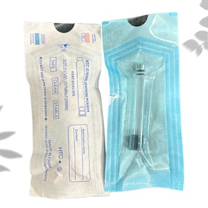 May include: Two sterile pouches. One is white with blue text and graphics, labeled "HTC-STERILIZATION POUCH." The other is clear with a medical instrument inside. The white pouch has the size 2¼"x5" (57mmx130mm) printed on it.