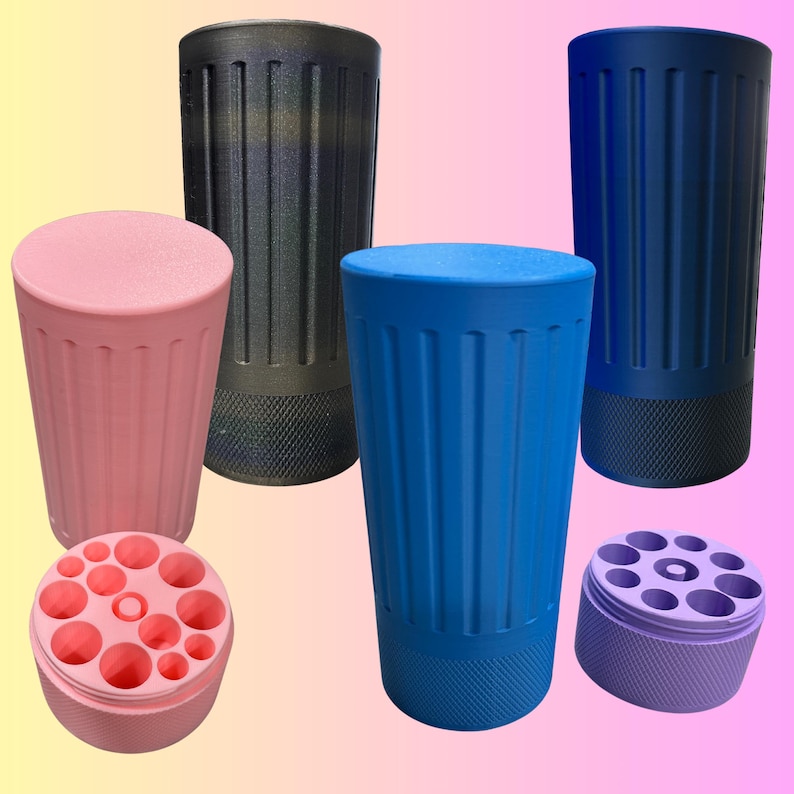 May include: A collection of cylindrical containers in various colors, including pink, blue, and black. The containers have a ribbed design and textured bases. One pink container is open, revealing multiple circular holes.