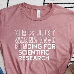 Puede incluir: Una camiseta color malva con el texto "Girls Just Wanna Have Funding For Scientific Research" impreso en blanco.