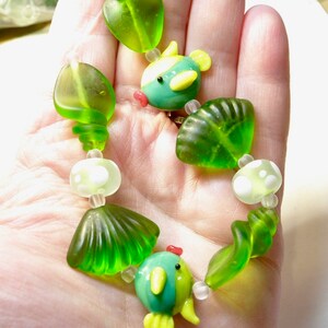 May include: A green and blue glass bead necklace with a seahorse and shell design.