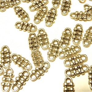 May include: A group of silver-toned metal connector charms with a woven design. The charms are small and have a rectangular shape.