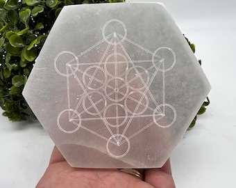 May include: White selenite charging plate with a etched geometric design. The design is a flower of life pattern.
