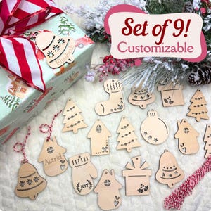 May include: Set of nine customisable wooden Christmas decorations. The decorations feature various shapes, including a bell, a stocking, a tree, a house, a mitten, and a gift box. The decorations are made of natural wood and have a rustic, farmhouse style.