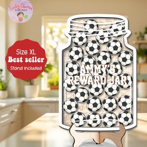 May include: A wooden reward jar shaped like a mason jar, filled with soccer balls. The jar has the text "AMMY'S REWARD JAR" and sits on a wooden stand. A red sticker says "Size XL Best seller Stand included".