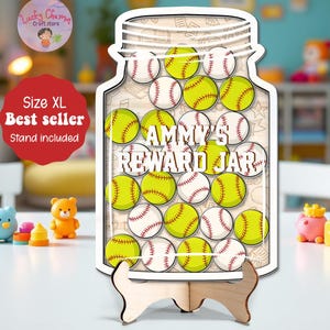 May include: A wooden reward jar shaped like a mason jar, filled with baseballs and softballs. The text "AMMY'S REWARD JAR" is displayed on the jar. The jar is on a wooden stand. The image also includes the text "Size XL" and "Best seller".