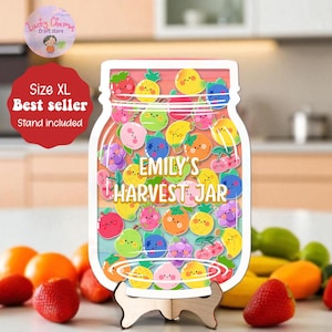 May include: A wooden jar-shaped sign with a colorful fruit design, including strawberries, lemons, and pineapples. The sign reads "Emily's Harvest Jar" and comes with a wooden stand. The sign is a best seller.