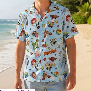 Op de afbeelding: Lichtblauw Hawaii-shirt met korte mouwen met een herhalend patroon van stripfiguren. Het shirt heeft een knoopsluiting en een klassieke kraag. De tekst "Daniel" is op het shirt gedrukt. Onderdeel van een Hawaii-set met all-over print.