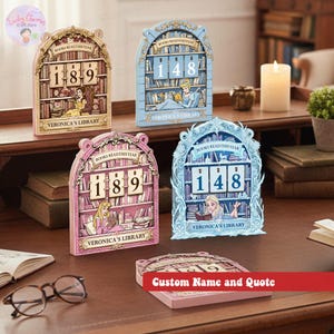 May include: A collection of decorative book-themed perpetual calendars in various pastel colors. Each calendar features a bookshelf design with a number display and a character illustration. The text "BOOKS READ THIS YEAR" and "VERONICA'S LIBRARY" are visible.