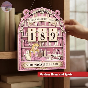 May include: A pink wooden bookshelf-shaped sign with the text "BOOKS READ THIS YEAR" and the numbers "189". The sign features a cartoon illustration of a woman reading a book, with the text "VERONICA'S LIBRARY" below. The sign is designed to be personalized.