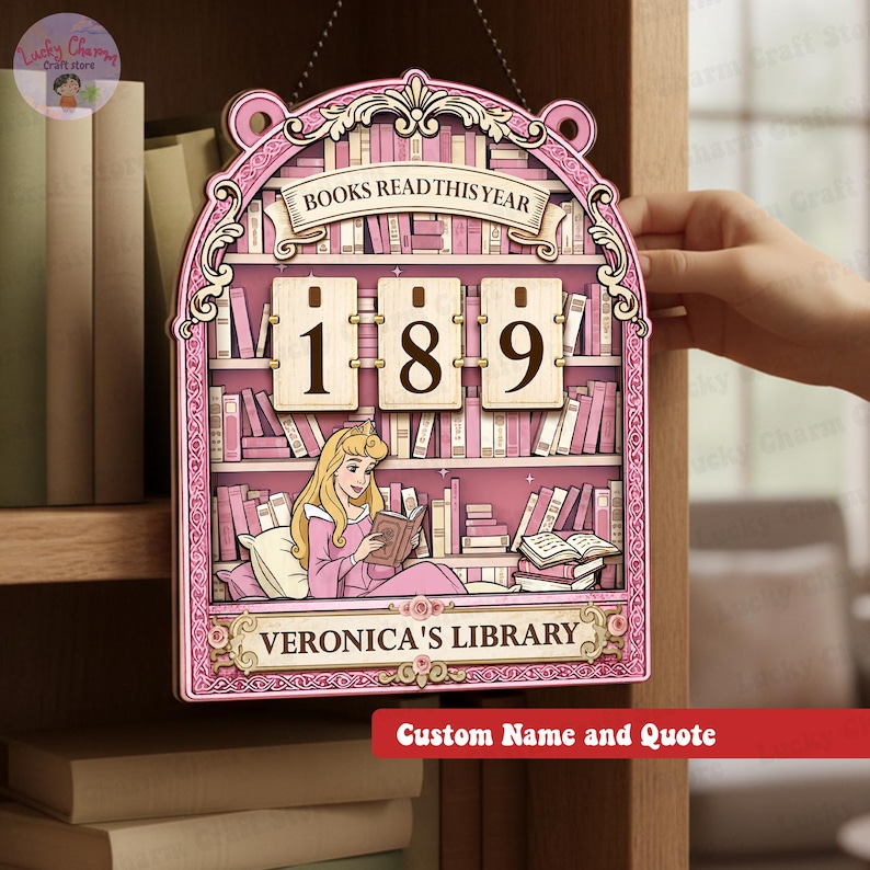 May include: A pink wooden bookshelf-shaped sign with the text "BOOKS READ THIS YEAR" and the numbers "189". The sign features a cartoon illustration of a woman reading a book, with the text "VERONICA'S LIBRARY" below. The sign is designed to be personalized.