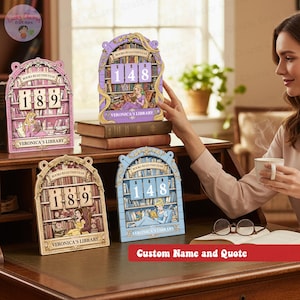 May include: Decorative wooden book-themed calendar with the text "BOOKS READ THIS YEAR" and a custom name. The calendar features a princess reading a book, with the numbers 189 and 148 displayed. Available in pink, gold, and blue.