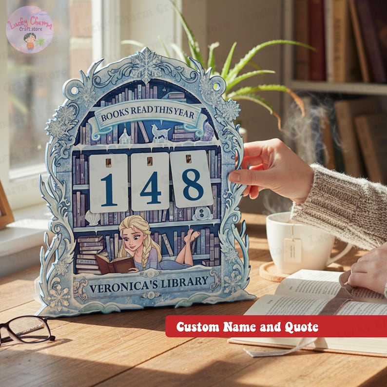 May include: A light blue wooden bookshelf-shaped calendar with the text "BOOKS READ THIS YEAR" and the numbers "148". The bottom of the calendar reads "VERONICA'S LIBRARY". The calendar has a decorative frame with floral and snowflake designs.