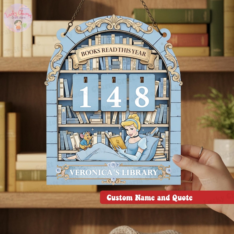 May include: A light blue wooden bookshelf-shaped sign with the text "BOOKS READ THIS YEAR" and the number "148". The sign features a Cinderella illustration reading a book, with the text "VERONICA'S LIBRARY" below. A red banner at the bottom says "Custom Name and Quote".