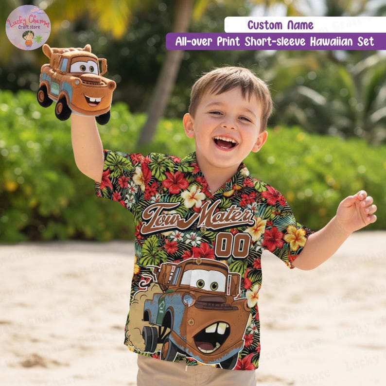 May include: A boy wearing a short-sleeved Hawaiian shirt with a Tow Mater cartoon design and floral pattern. The shirt features the text "Tow Mater 00". The boy is holding a Tow Mater plush toy.