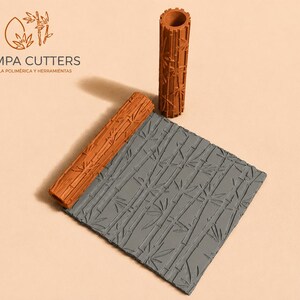 May include: Polymer clay tools with a bamboo pattern. The set includes a textured roller, a rectangular texture sheet, and a cylindrical roller. The tools are in shades of brown and grey. The brand name "PAMPA CUTTERS" is visible in the image.