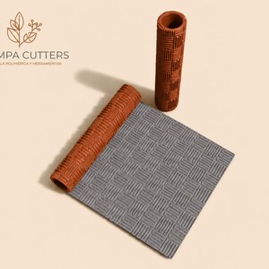 Puede incluir: Un juego de herramientas para arcilla polimérica, que incluye un rodillo texturizado y una esterilla estampada con un diseño de cesta tejida. El rodillo y la esterilla son de color marrón y gris. La marca "PAMPA CUTTERS" es visible.