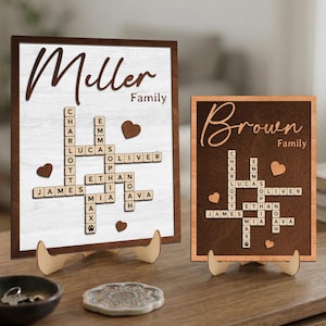 May include: Two wooden family name signs. One sign is white with the name "Miller" and a crossword puzzle of names. The other sign is brown with the name "Brown" and a crossword puzzle of names. Both signs have heart accents.