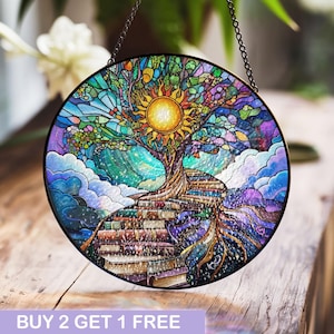 May include: A stained glass window hanging features a colorful tree with a sun at the top and a path of books leading to the roots. The tree is surrounded by clouds and a starry sky.