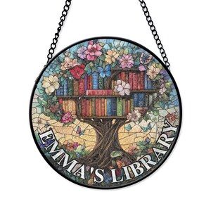 May include: A round stained glass window hanging with a black chain. The window features a tree with books on the branches and the text "Emma's Library". The tree has colorful flowers and butterflies.