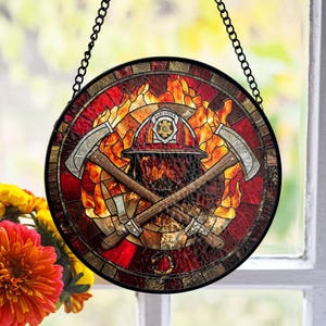 Puede incluir: Arte de ventana de vidriera redonda con un casco de bombero, hachas cruzadas y llamas en tonos rojos, naranjas y amarillos. El diseño incluye un marco y cadena de metal negro para colgar. Una pieza decorativa para entusiastas del servicio de bomberos.