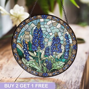 May include: A stained glass window hanging with a chain. The window is round and features a mosaic design of bluebonnet flowers in shades of blue and green.
