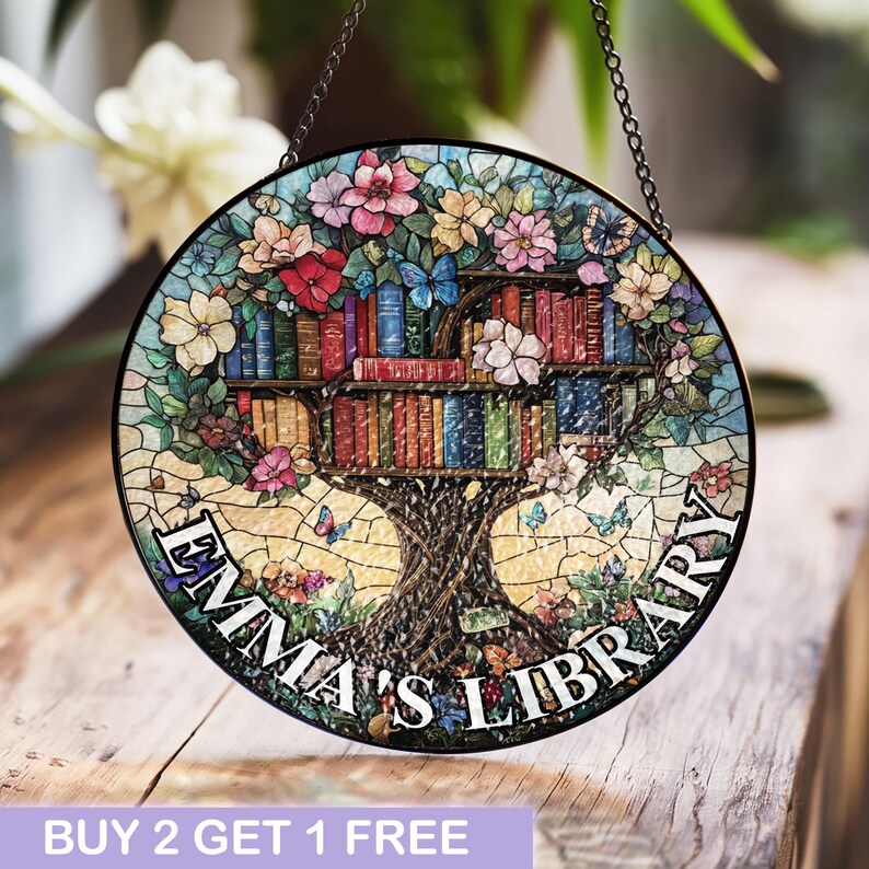 May include: A stained glass window hanging with a tree design. The tree has books on its branches and the text "Emma's Library" around the bottom.