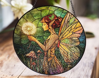May include: A stained glass window hanging depicts a fairy with wings holding a dandelion. The fairy has red hair and a green dress. The background is a green and yellow forest scene with mushrooms.