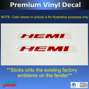 May include: Premium vinyl decal featuring two red "HEMI" emblems. The text "NOTE: Color shown in picture is for illustrative purposes only" is above the emblems. The text "**Sticks onto the existing factory emblems on the fender**" is below the emblems.
