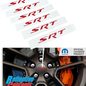 May include: Six white stickers with red "SRT" lettering. The stickers are arranged in a stack, with the top sticker partially covering the sticker below it. The stickers are on a white background. A close-up of a car wheel with a black and orange brake caliper. The wheel has a silver center cap with a red "SRT" logo. The wheel is on a black background. The image also includes the Mopar logo and the text "Official Licensed Product".