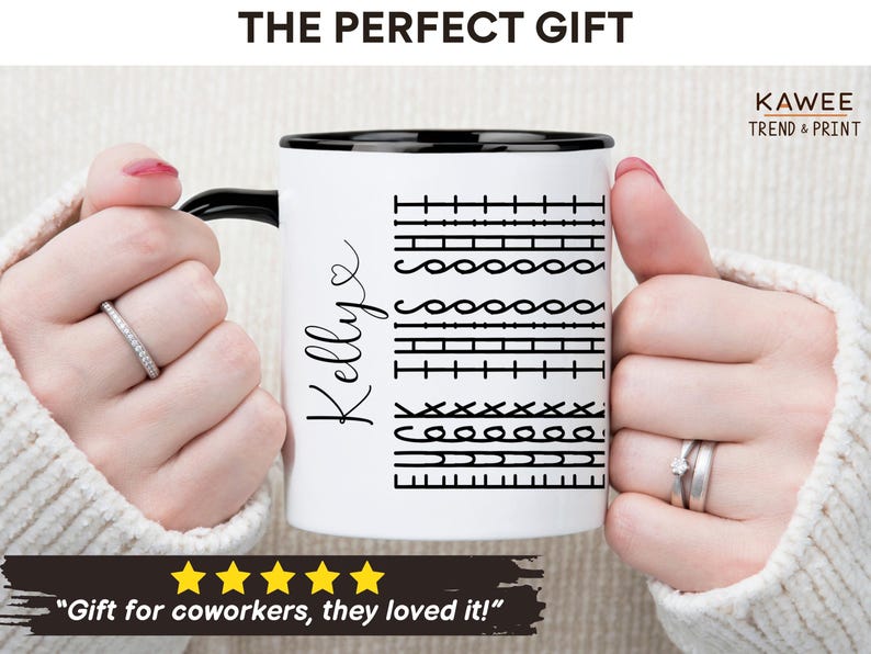 May include: White ceramic mug with a black rim and handle. The mug has a black and white graphic of different sewing stitches and the name "Kellye" written in cursive. The mug is being held by a person's hands.