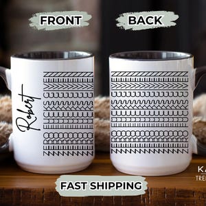 May include: White ceramic mug with a black rim and handle. The mug has a black and white geometric pattern on the front and back. The front of the mug is personalized with the name "Robert".