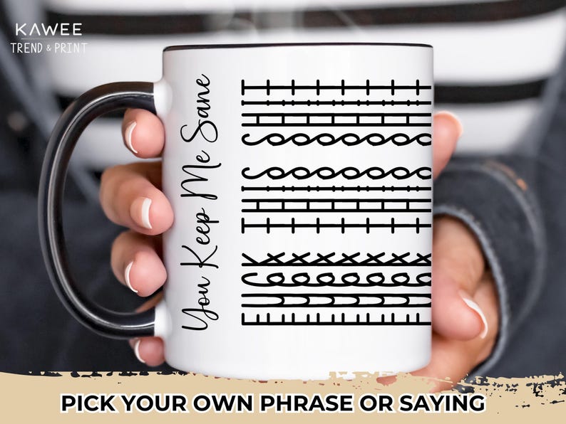 May include: White ceramic mug with a black rim and handle. The mug has black text that says "You Keep Me Sane" and a pattern of different stitches.