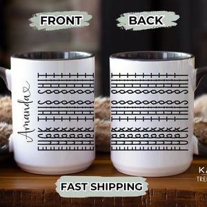 May include: A white ceramic mug with a black rim and handle. The mug has a black and white pattern on the front and back. The front of the mug has the name "Amanda" written on it.