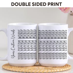 May include: Two white ceramic mugs with black designs. The mug on the left has the text "Your Custom Words" printed on it. The mug on the right has a pattern of black lines and shapes. The mugs are on a light brown surface.