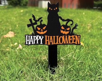 Może przedstawiać: Czarna metalowa ozdoba ogrodowa z sylwetką kota, dwiema dyniami, krzyżem i nietoperzem. Napis "HAPPY HALLOWEEN" wykonany jest pomarańczowymi i białymi literami u podstawy tego dekoracyjnego znaku przeznaczonego do wbicia w ziemię.