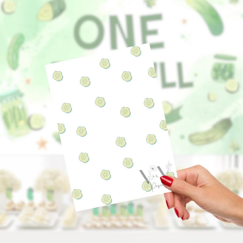 Puede incluir: Una tarjeta blanca con un patr&oacute;n de rodajas de pepinillos verde claro se sostiene en una mano con esmalte de u&ntilde;as rojo. El fondo presenta las palabras "ONE PILL" y un dise&ntilde;o de acuarela de pepinillos y tarros.