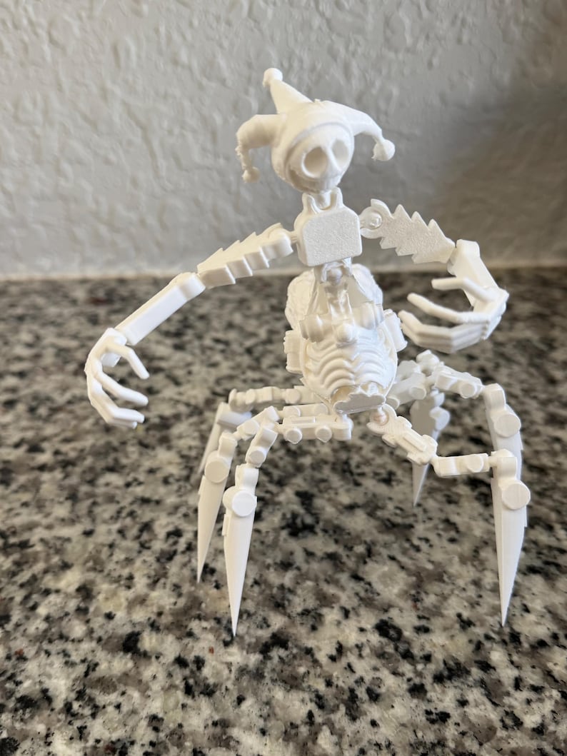 Puede incluir: Una figura blanca articulada que se asemeja a un buf&oacute;n. La figura tiene un sombrero puntiagudo, una cara esquel&eacute;tica y extremidades articuladas. Tiene m&uacute;ltiples piernas y brazos, y est&aacute; posada como si estuviera bailando o movi&eacute;ndose.
