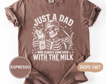 Könnte beinhalten: Espressofarbenes T-Shirt mit einer Grafik eines Skeletts mit Sonnenbrille und Baseballkappe, das einen Milchkarton hält. Der Text lautet "JUST A DAD WHO ALWAYS CAME BACK WITH THE MILK."