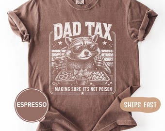 Könnte beinhalten: Braunes T-Shirt mit einem Waschbären mit Sonnenbrille, der ein Getränk und Snacks hält. Der Text lautet "DAD TAX" und "MAKING SURE IT'S NOT POISON".
