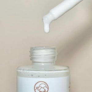 May include: A white dropper bottle with a white cap and a white dropper. The bottle is filled with a white liquid. The bottle has a label with a camel and mountains on it.