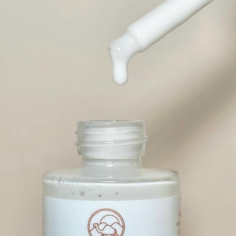 May include: A white dropper bottle with a white cap and a white dropper. The bottle is filled with a white liquid. The bottle has a label with a camel and mountains on it.