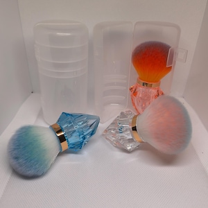 Pode incluir: Um conjunto de pincéis de maquiagem com cabos transparentes em forma de diamante e cerdas coloridas. Os pincéis apresentam gradientes de cores, incluindo azul, laranja e rosa. Estojos de plástico transparentes também são visíveis.