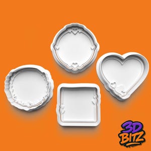 May include: Four white cookie cutters in various shapes: a circle with a scalloped edge, a circle with a decorative border, a square, and a heart. Each cutter features a heart design. The background is orange.