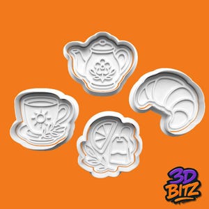 May include: Four white plastic cookie cutters shaped like a teapot, a teacup with a sun design, a croissant, and a tea bag with a lemon slice. The cutters are on an orange background. The 3D BITZ logo is in the bottom right corner.