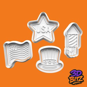 May include: Four white 3D-printed cookie cutters in the shape of patriotic symbols. The shapes include a star with "USA" text, a waving American flag, a top hat, and a firework. The background is orange.